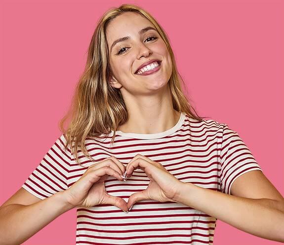 Mujer haciendo un corazón con sus manos sobre su pecho indicando una buena salud cardiovascular.
